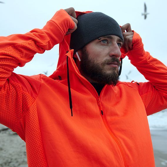 A man with a beard wearing an orange jacket and a black beanie