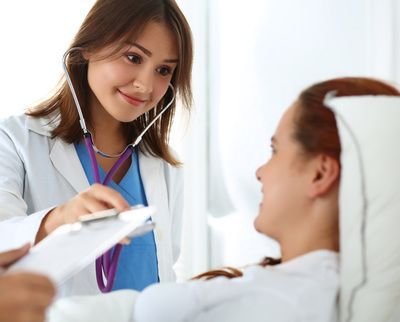 A doctor is listening to a patient 's heartbeat with a stethoscope.