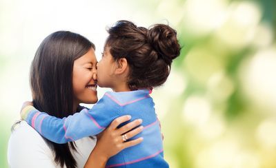 A woman getting a kiss from her daughter