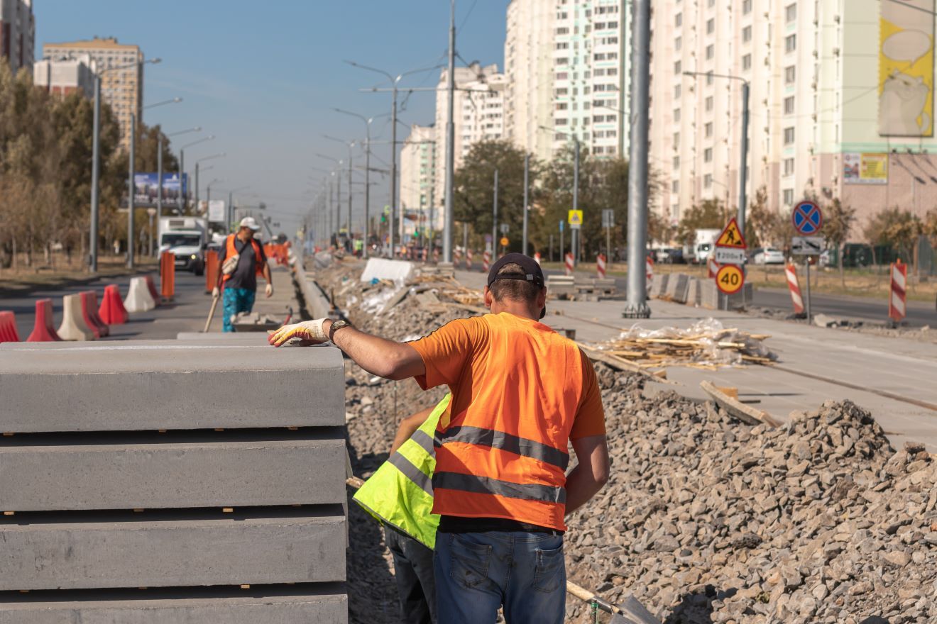 A Couple Of Construction Workers Are Walking Down A Street