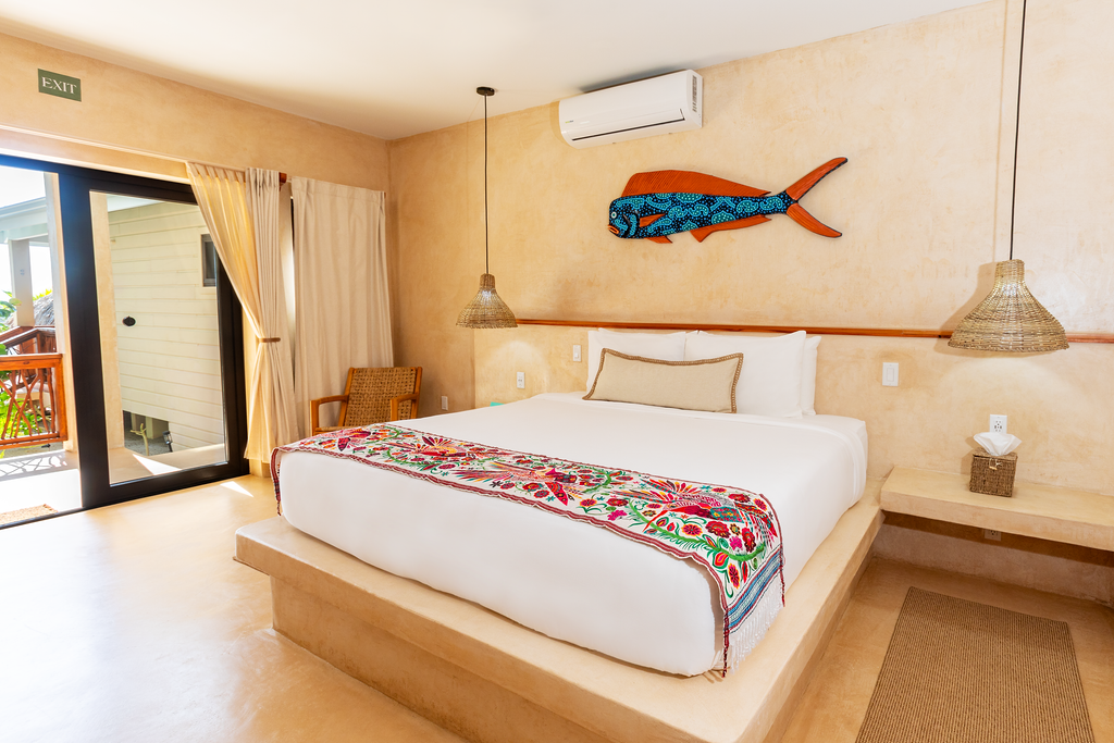 Bright bedroom with a white bed, fish wall art, woven lamp, and sliding glass doors to a patio