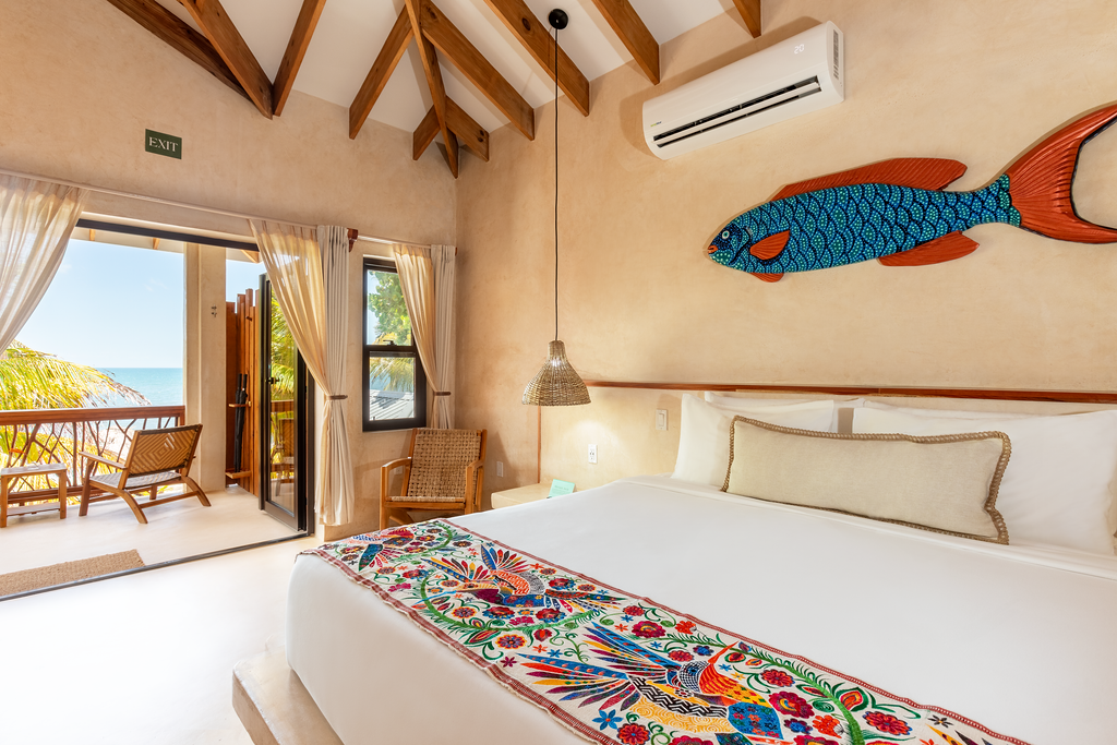 Bright tropical bedroom with bed, colorful decor, wood beams, and open balcony view