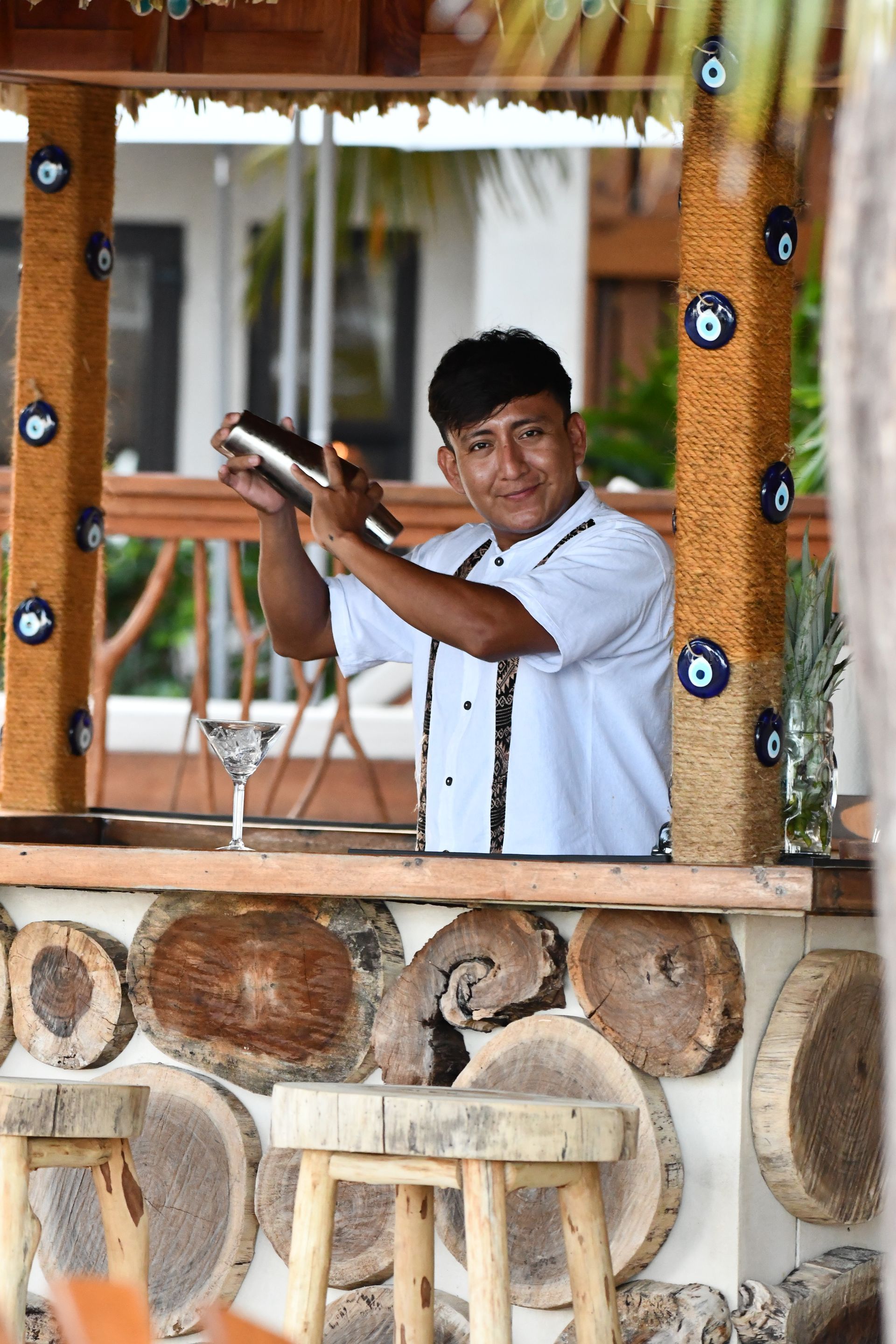 Bartender shaking a cocktail at a rustic outdoor bar with wood and stone decor
