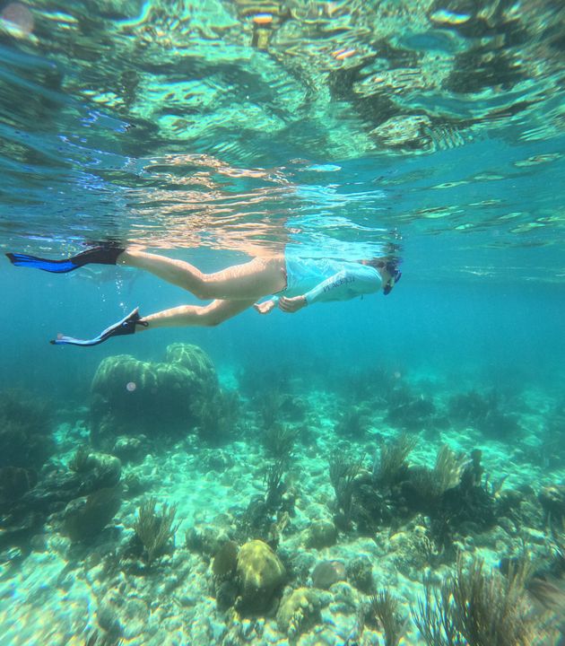 Snorkeler swimming over a coral reef in clear turquoise water