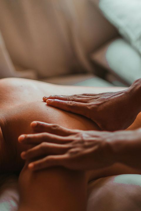 Hands massaging a person’s back on a spa bed in warm light