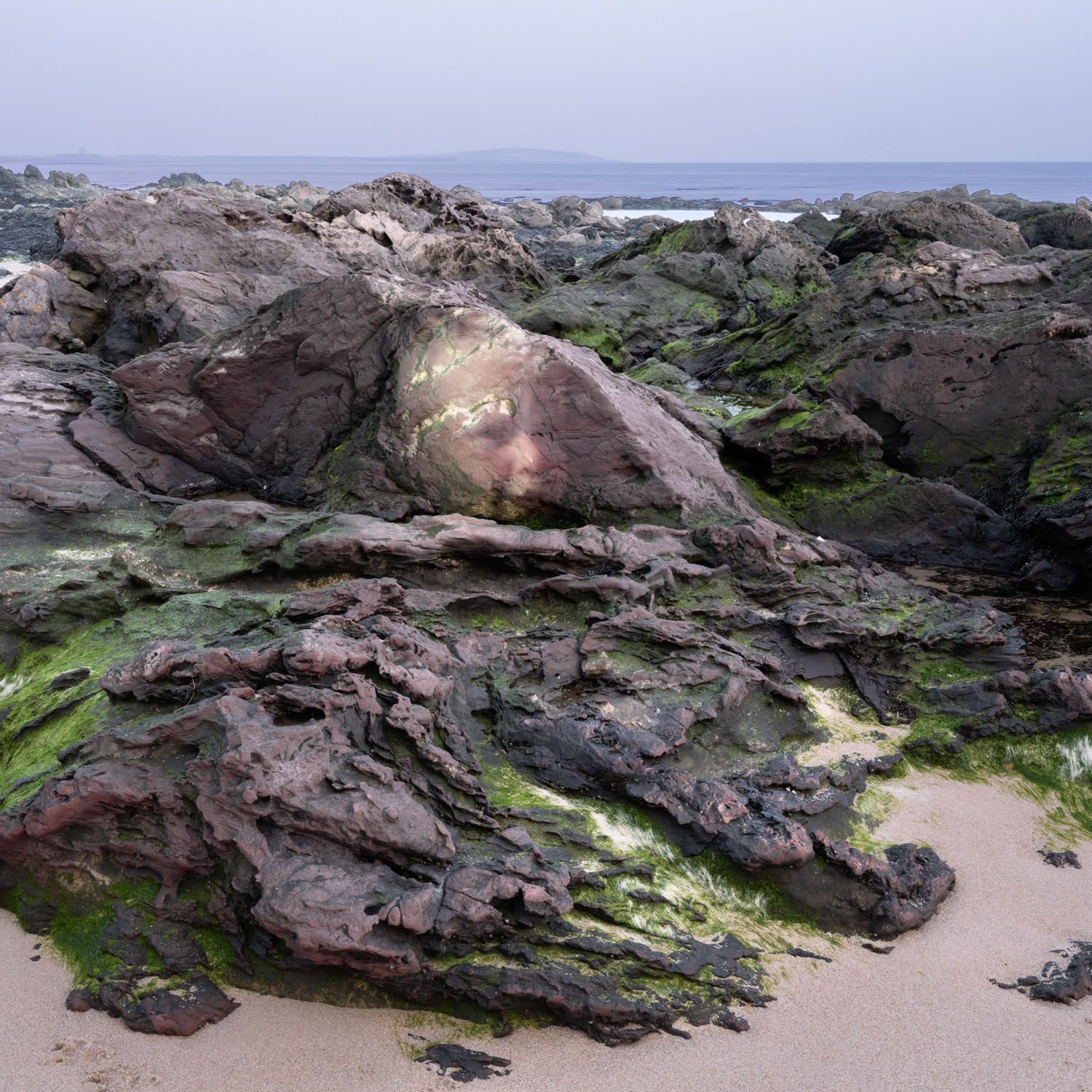 The Rock Projections evoke the Green Man motif and draw on the folklore of Land Spirits, where spirits inhabit rocks and where rocks are believed to perceive the world around them. The stone tape theory states that rocks can capture and replay past events. I have projected my face as a baby and young boy onto lichen and moss-covered rocks and boulders in places I feel my spirit lives; places that hold an emotional connection for me from my childhood.
