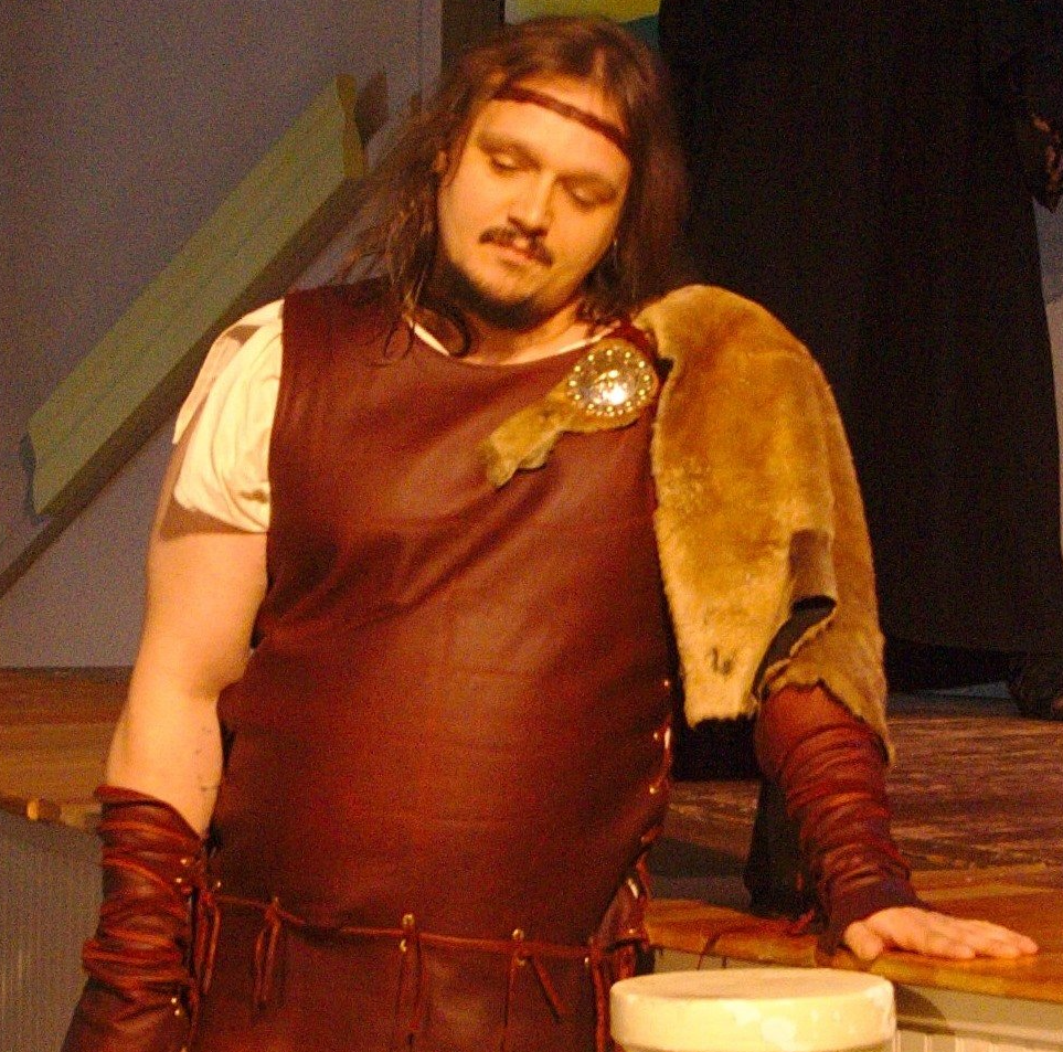A man in a brown leather outfit is standing on a stage