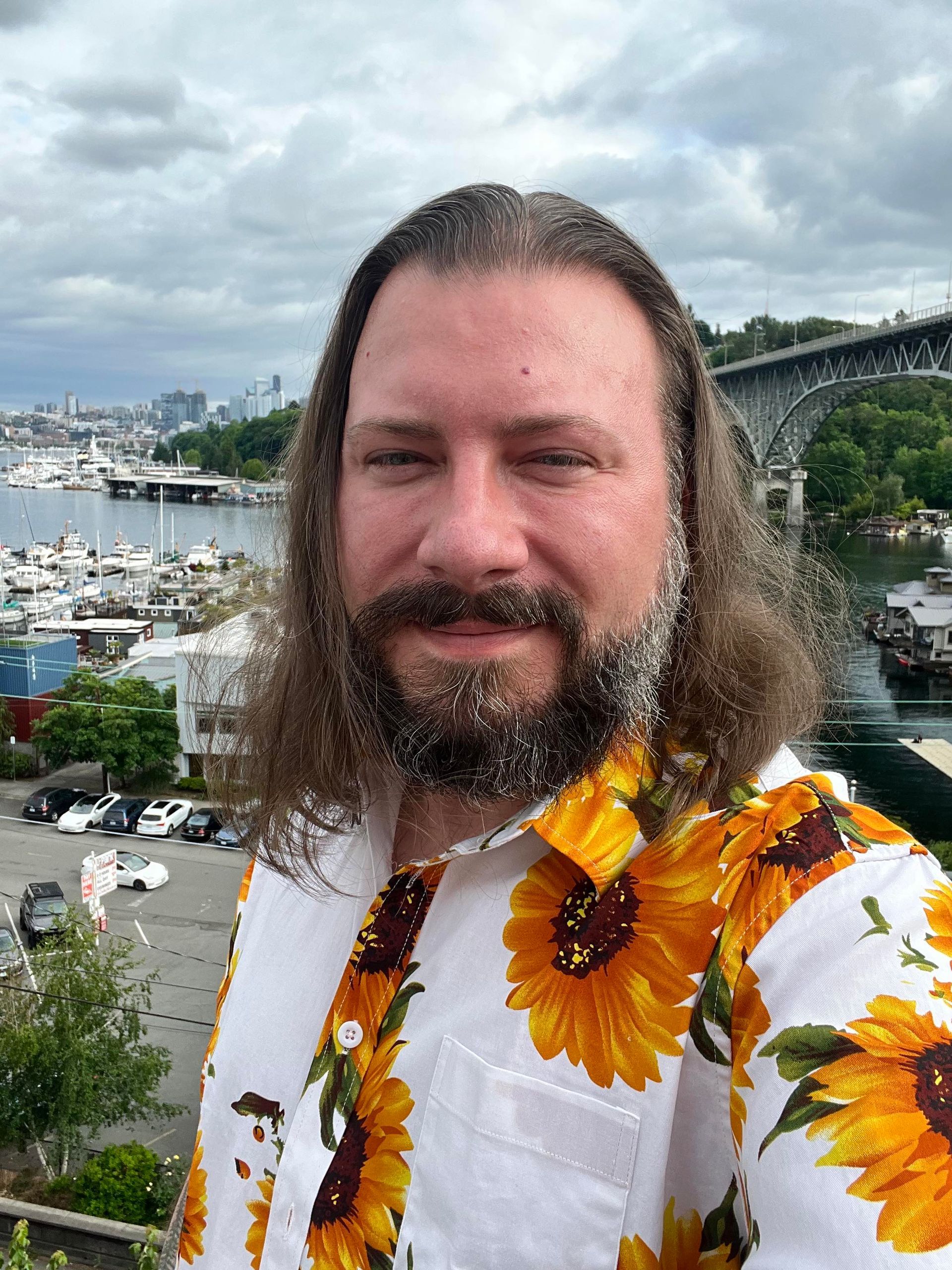 A man with long hair and a beard is standing in front of trees, Terry Riley.