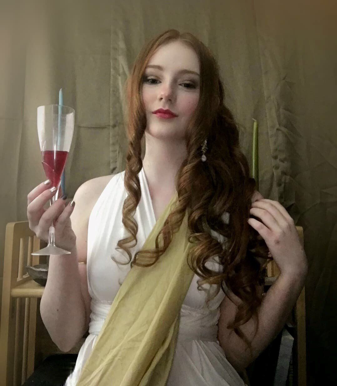 A woman in a white dress is holding a glass of wine