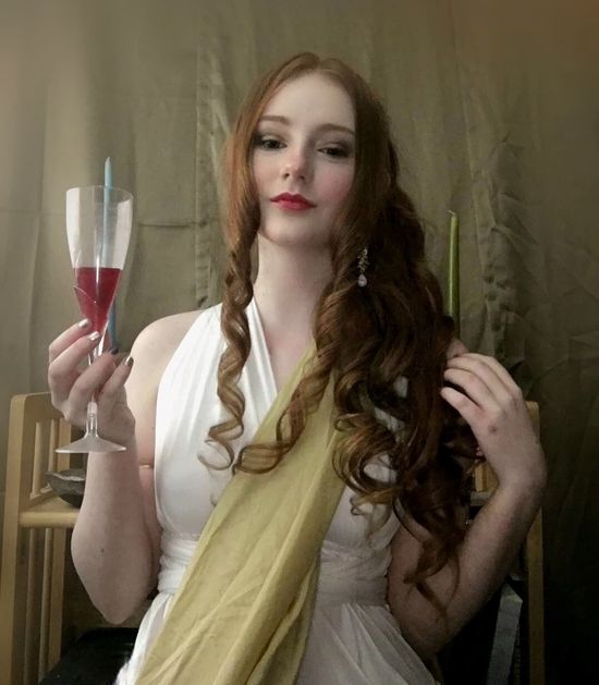 A woman in a white dress is holding a glass of wine