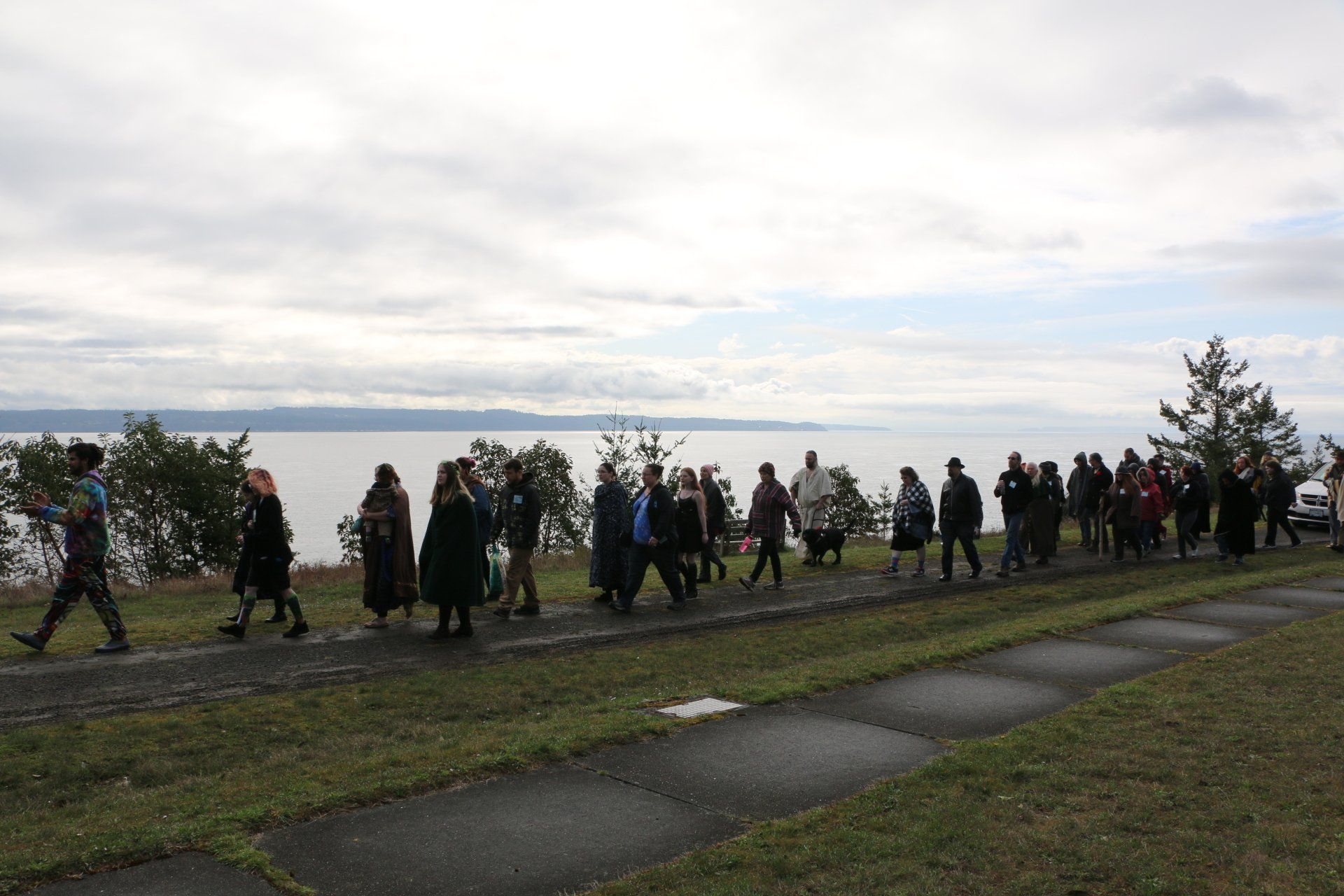 A group of people are walking down a path next to a body of water.
