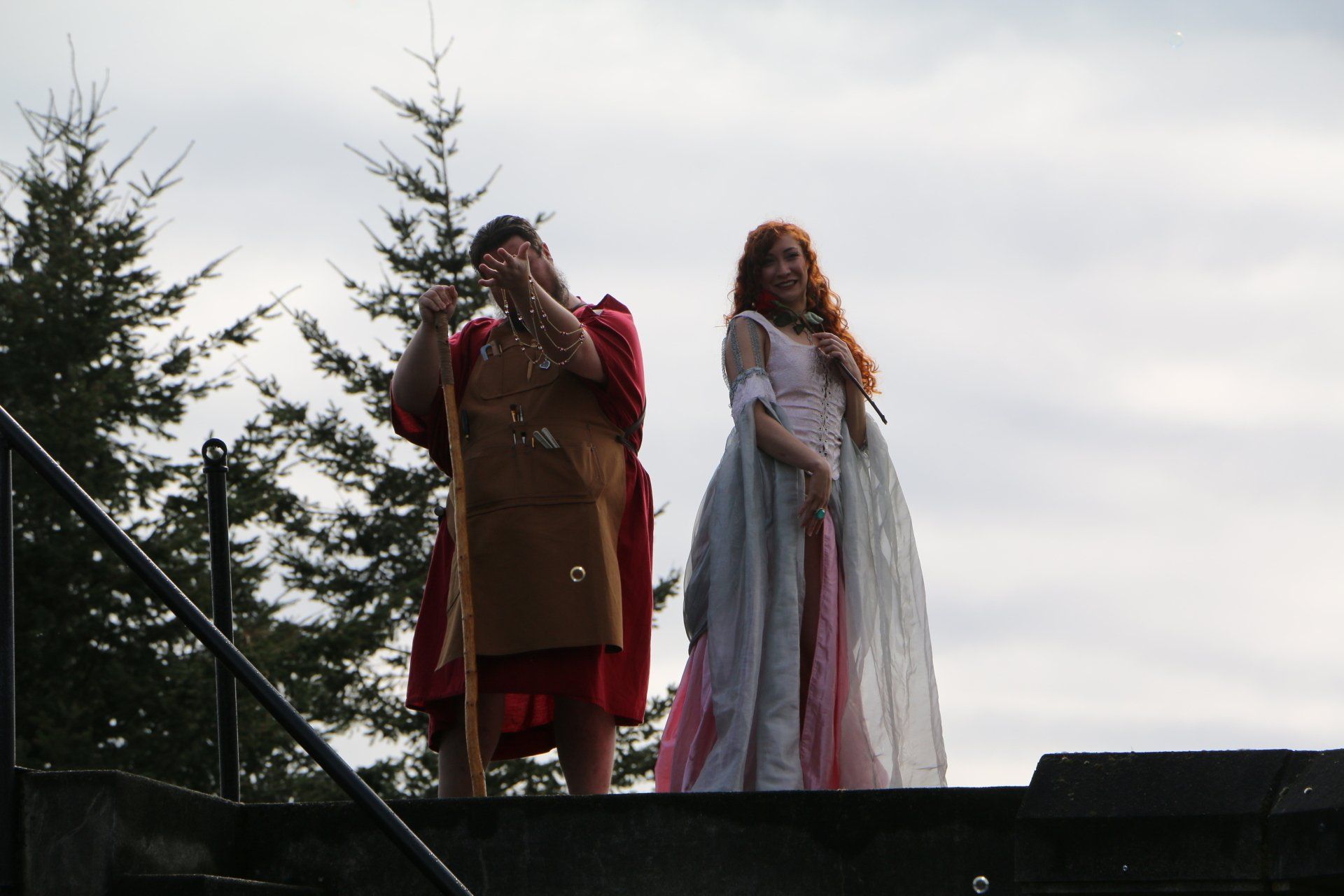 A man in a red robe stands next to a woman in a white dress