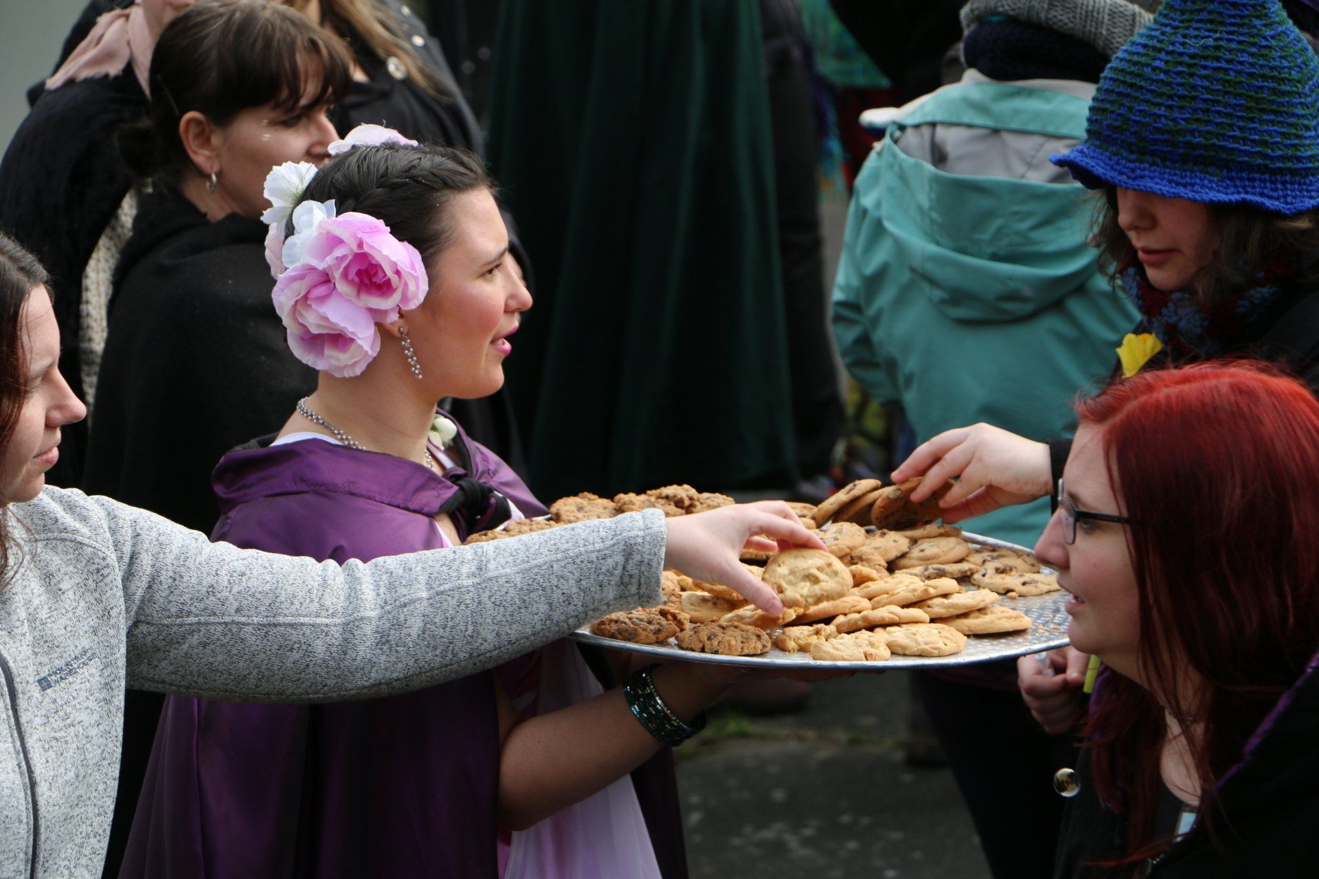 A woman in a purple dress is holding a tray of cookies