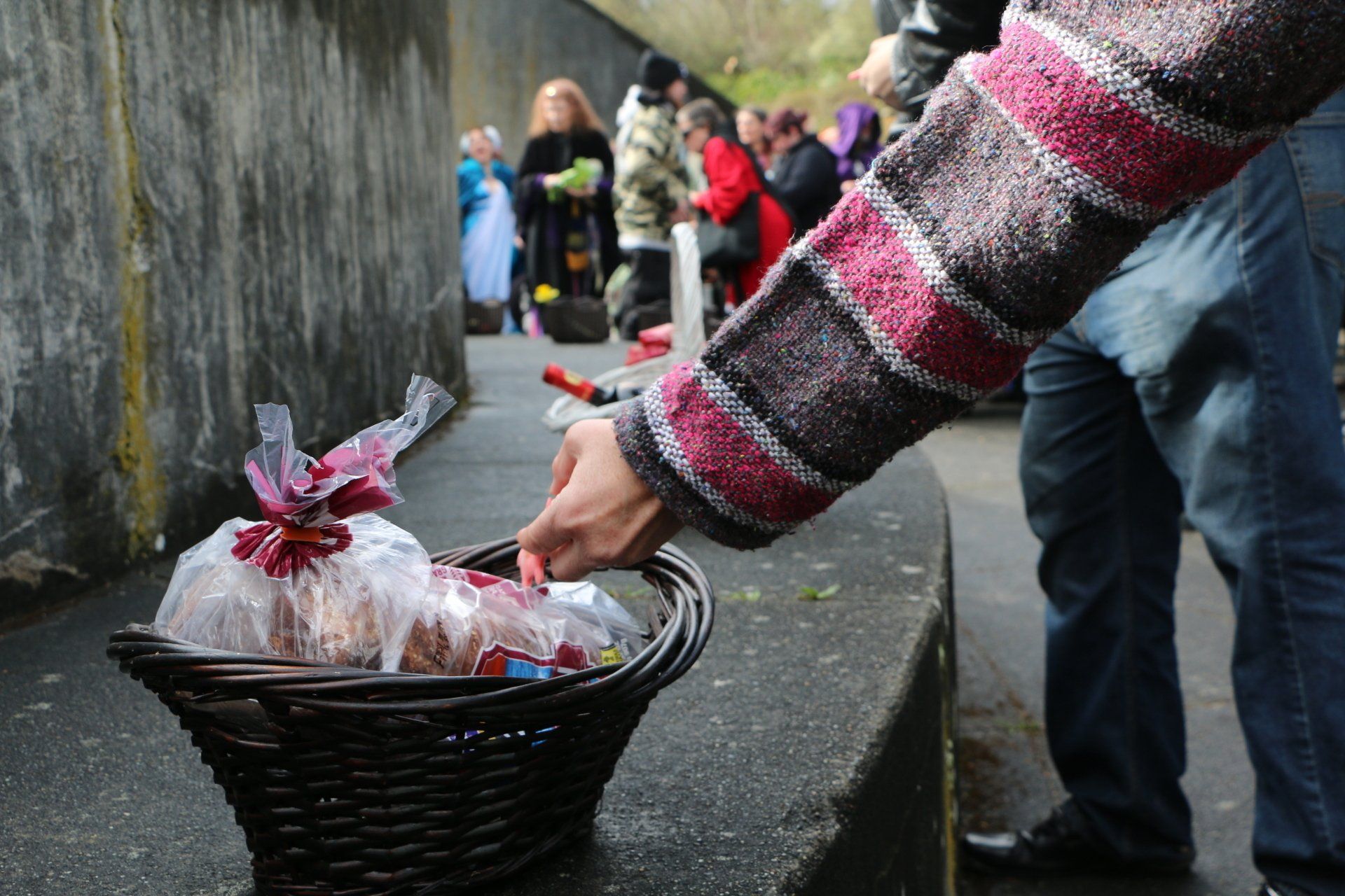 A person is putting something in a basket on the sidewalk