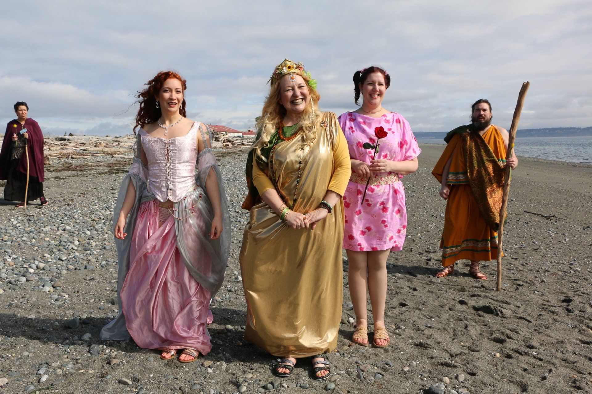 A group of people dressed in costumes are standing on a beach