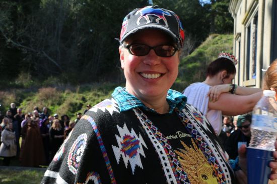 A woman wearing a hat and sunglasses is smiling for the camera