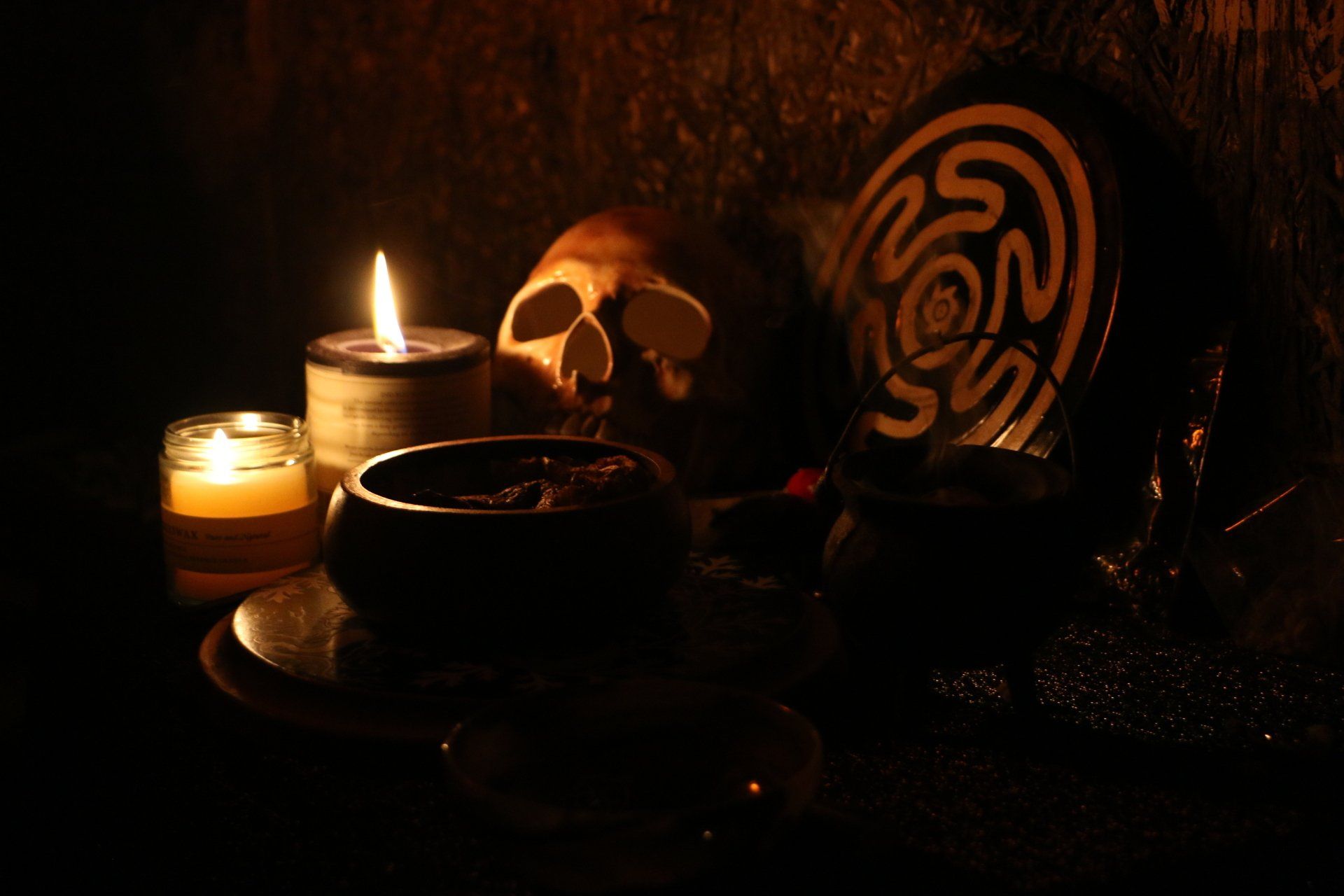 A skull and a candle are on a table in the dark.