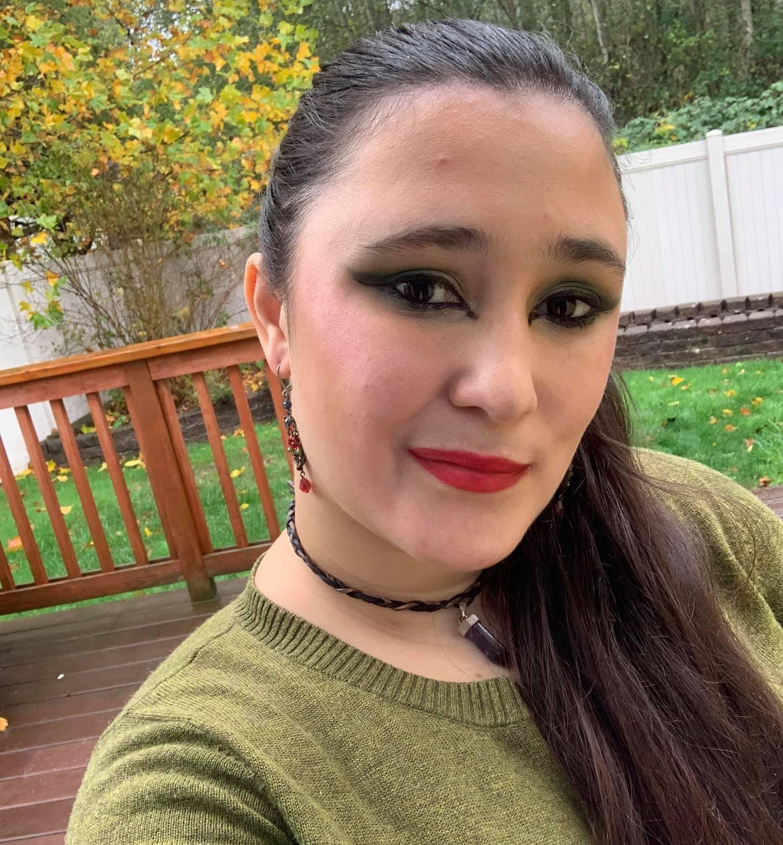A woman wearing a green sweater and red lipstick, Raven Wolfenone