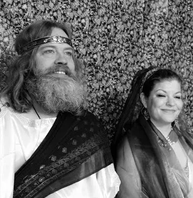 A man with a beard is standing next to a woman in a black and white photo.
