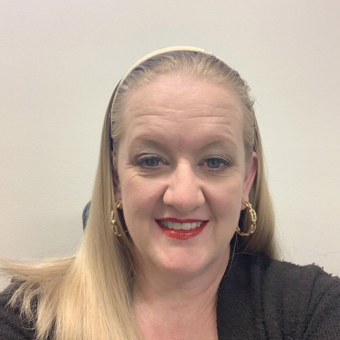 A woman wearing a headband and earrings is smiling for the camera, Amy Cochran.