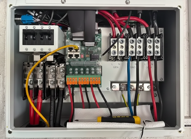 Electrical box with red, black, and yellow wires connected to terminal blocks and a circuit board.