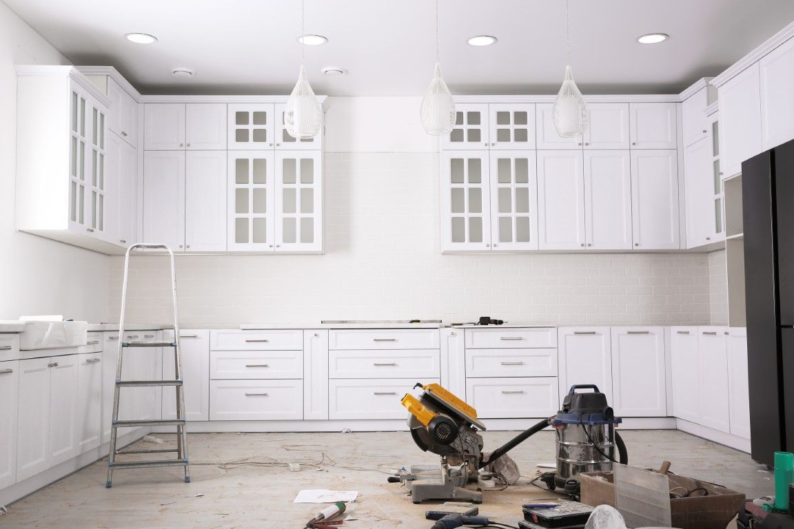 White kitchen cabinets installed, construction tools on floor.