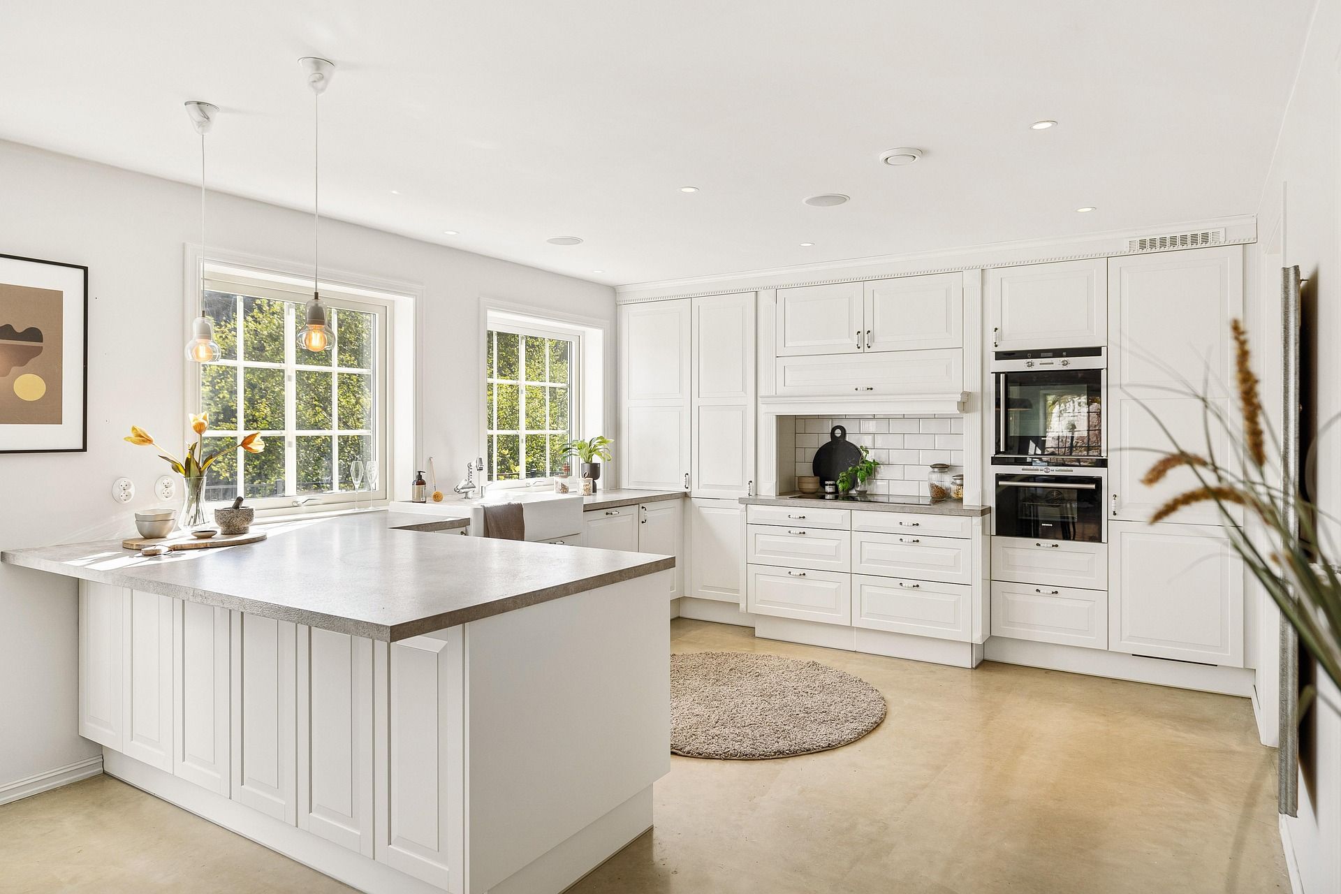 White kitchen with large island, pendant lights, and bright windows in Sun City West, AZ