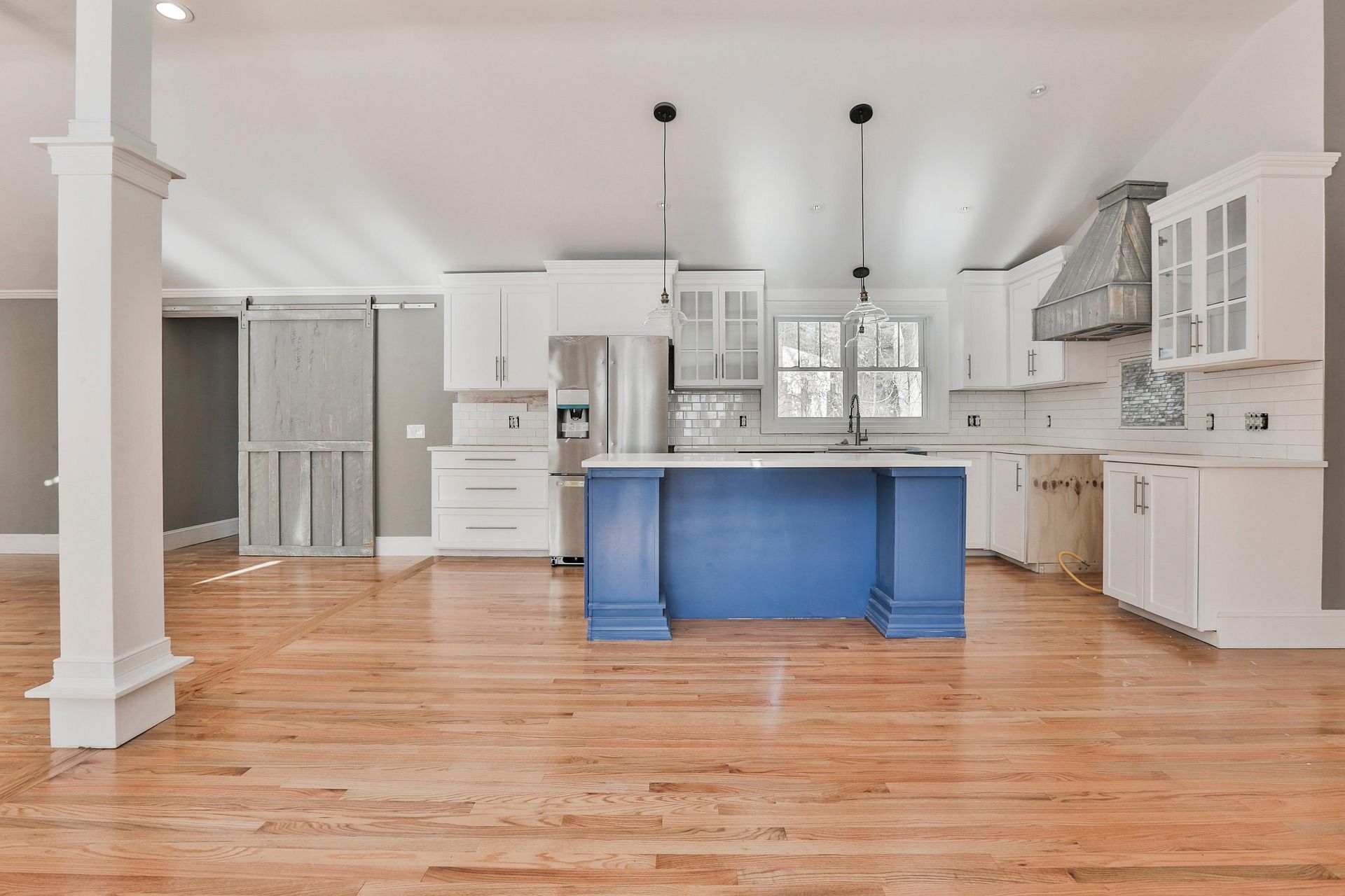 Open white kitchen with blue island and wood floors for kitchen remodeling in Waddell, AZ