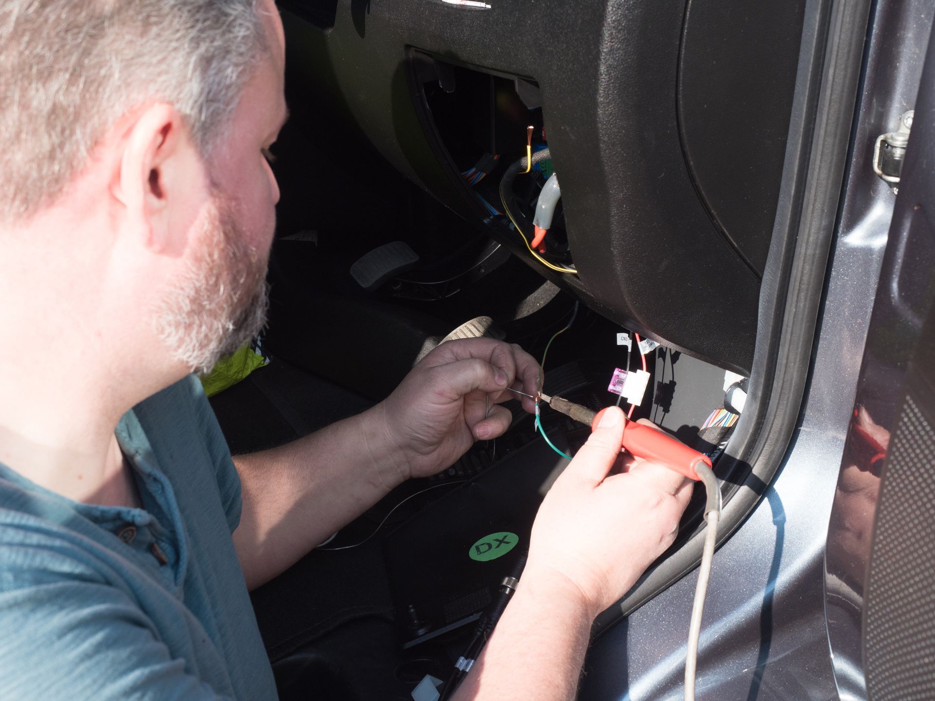 A person wearing black gloves is cleaning a car seat with a brush.