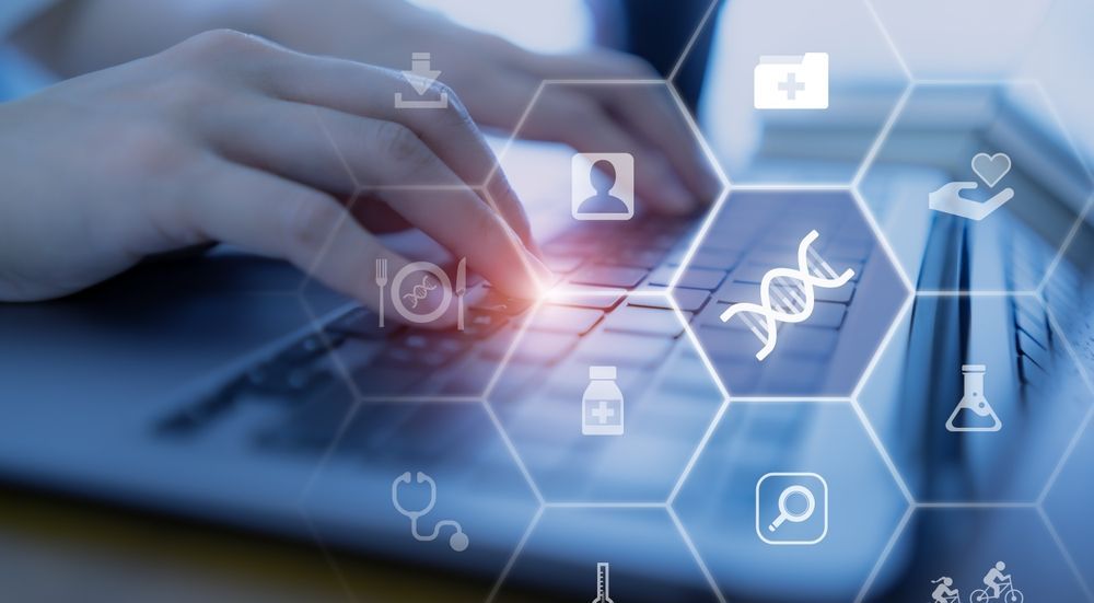 Hands typing on a laptop with blue medical data icons and DNA symbols overlayed.