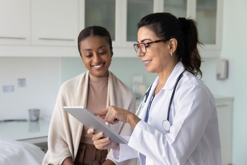 Doctor showing tablet to smiling patient in a bright clinic