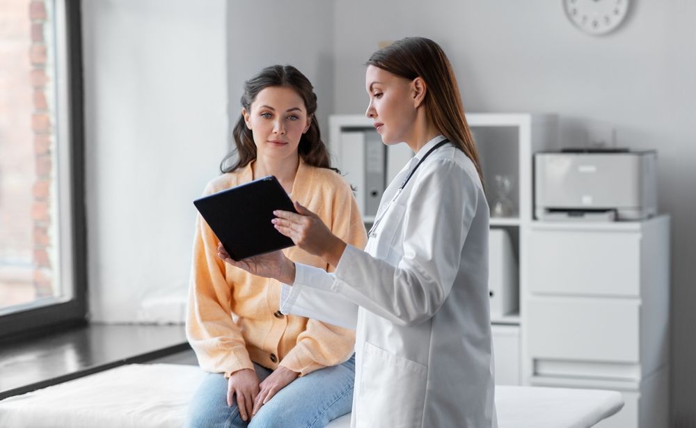 Doctor showing tablet to seated patient in a bright clinic room
