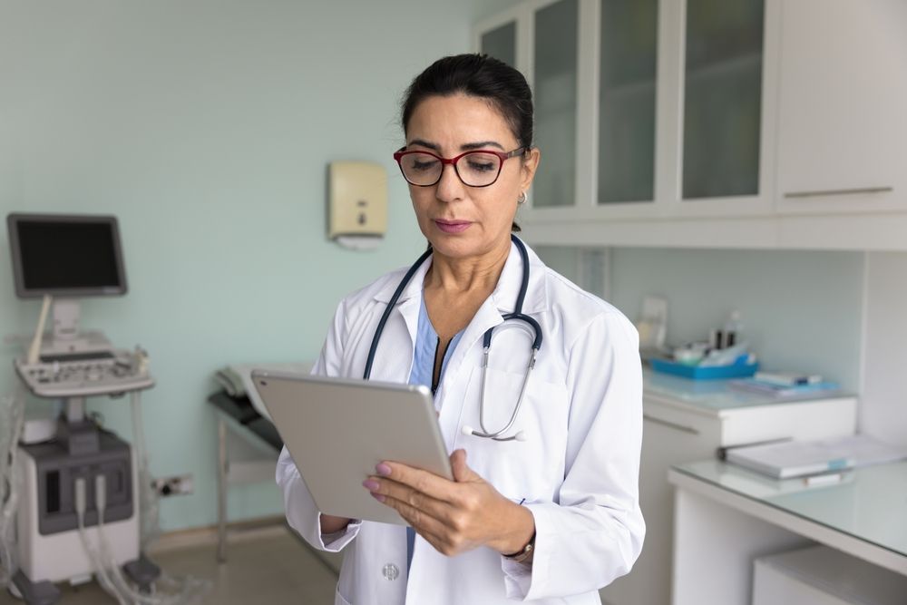 Doctor in a clinic holding a tablet and reviewing patient information