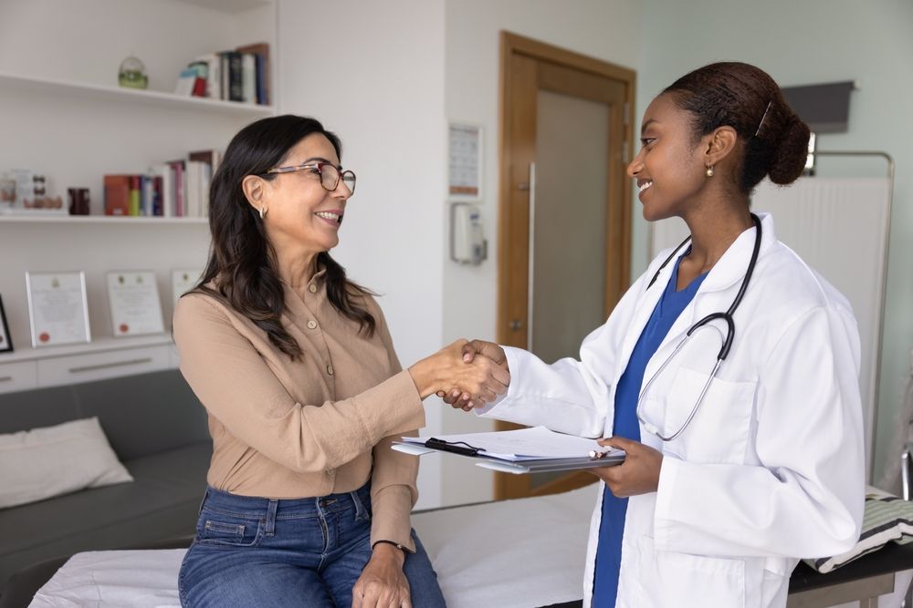 Doctor shaking hands with a patient in a clinic room.