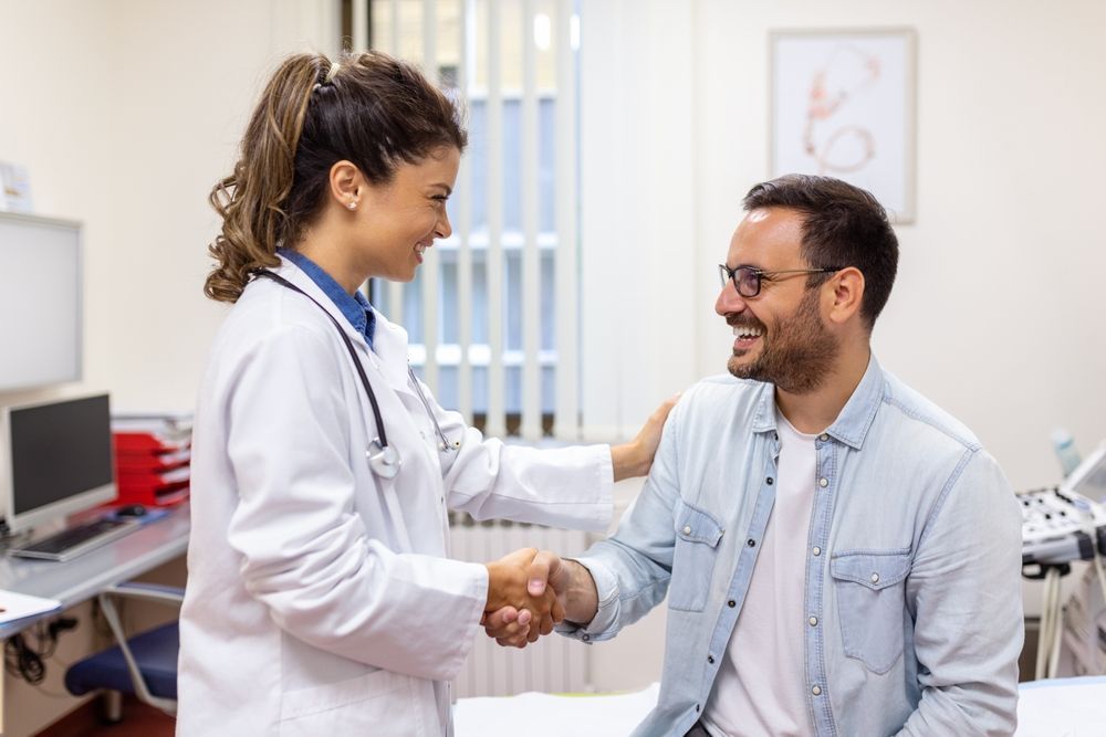 Doctor shaking hands with a smiling patient in a bright clinic office