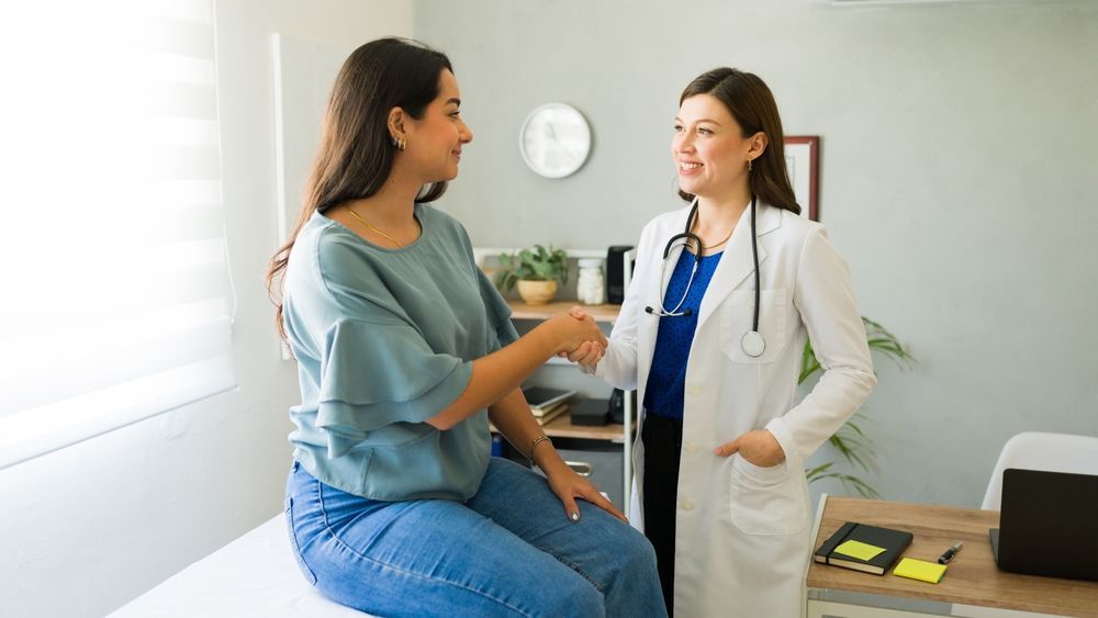 Doctor talking with a seated patient in a bright exam room