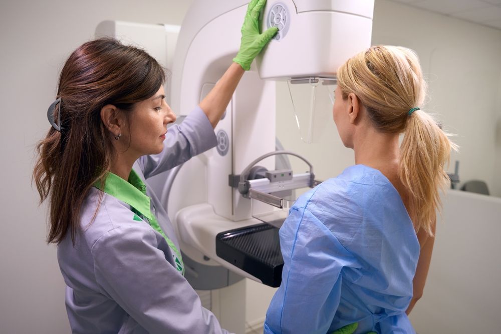 Two clinicians adjusting a mammography machine in a medical imaging room