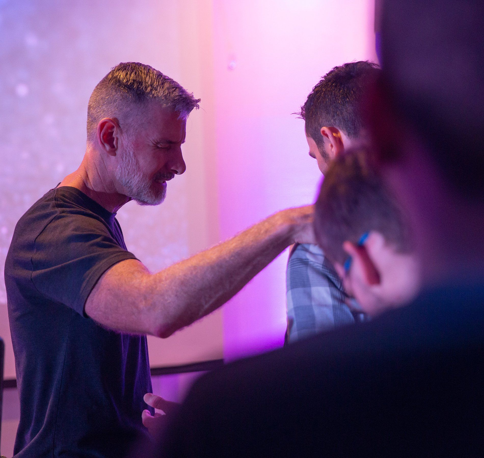 A man is praying with another man in a church.