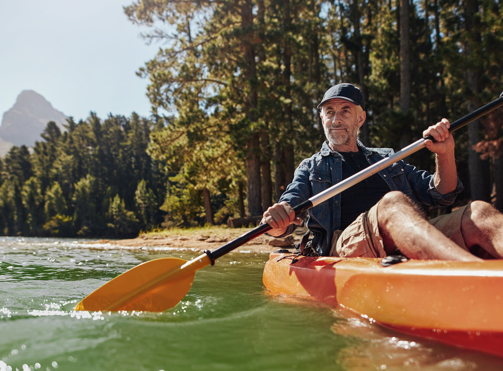 A man is paddling a kayak on a river.