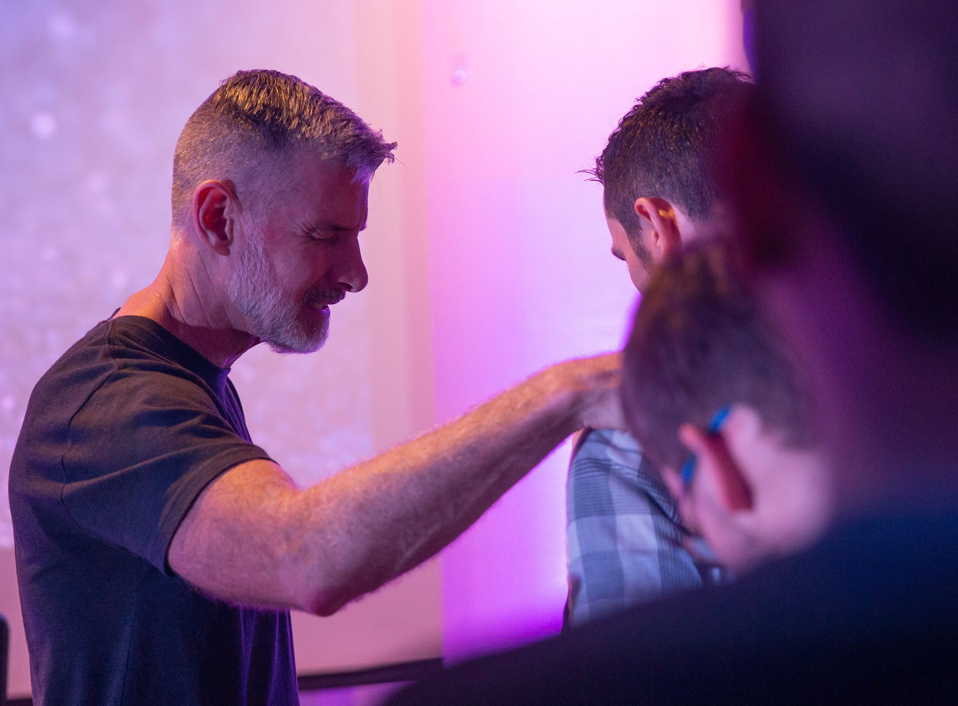 A man is praying with another man in a church.