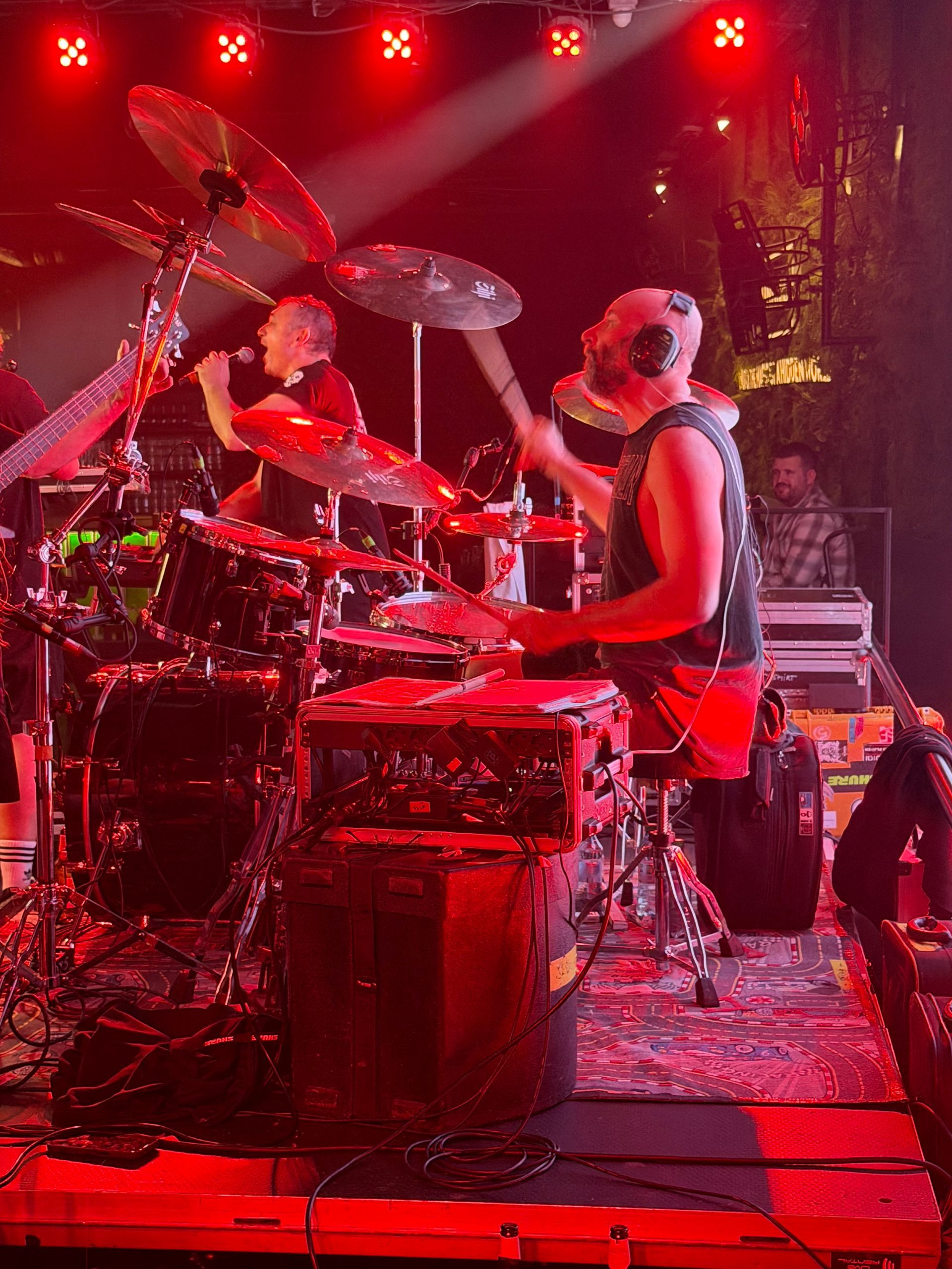 Drummer die optreedt op een rood verlicht podium met meerdere bekkens en percussie-instrumenten.