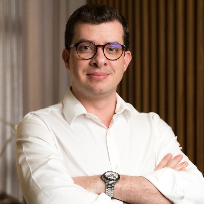 Um homem usando óculos e um relógio está de pé com os braços cruzados