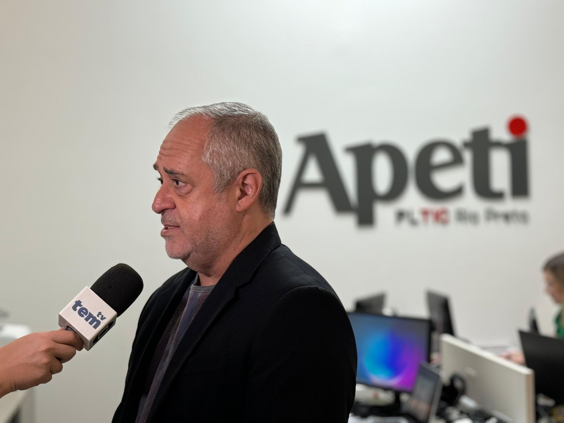 Um homem está sendo entrevistado em frente a uma placa que diz apetit
