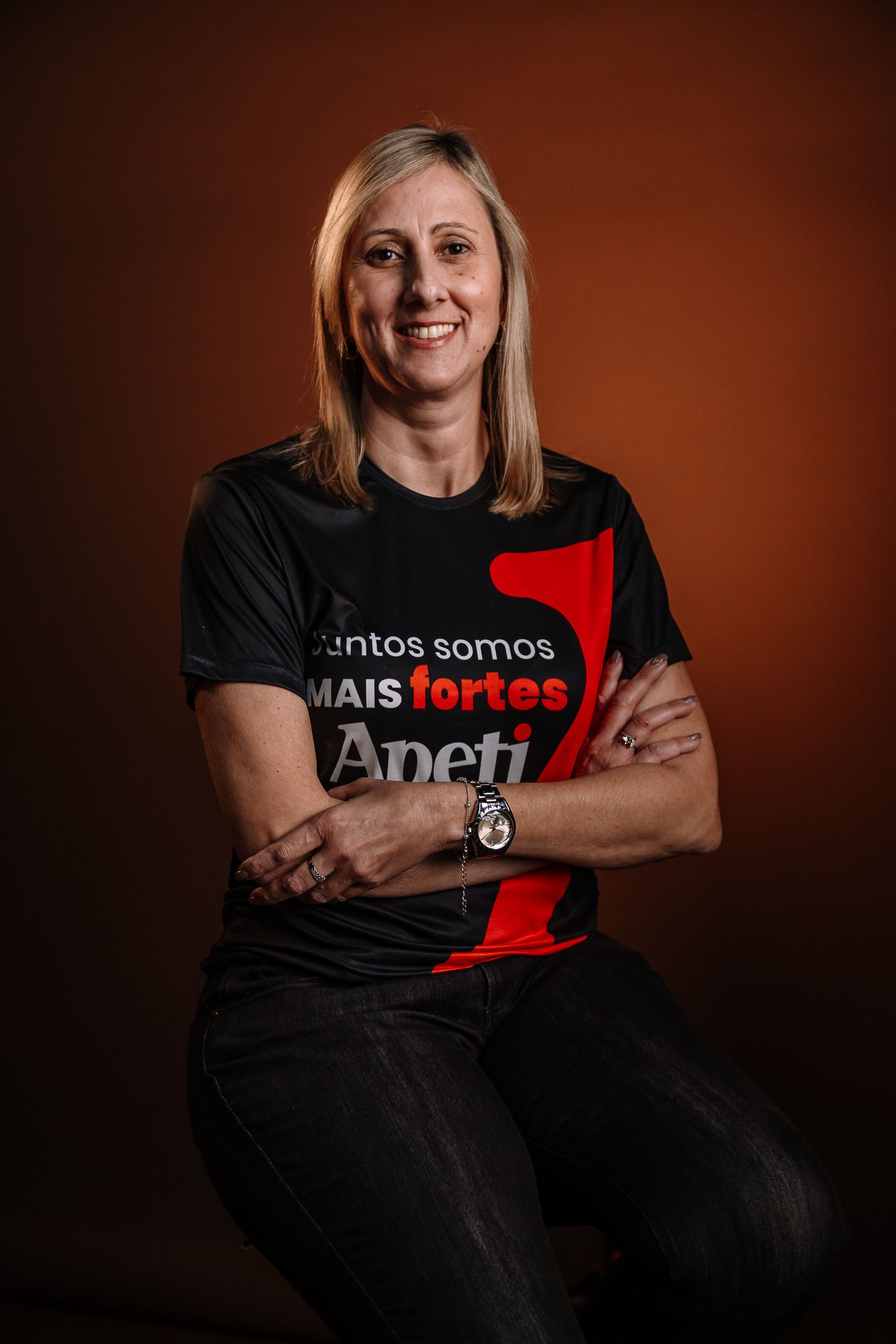 Uma mulher de cabelos loiros está vestindo uma jaqueta preta e uma camisa rosa.