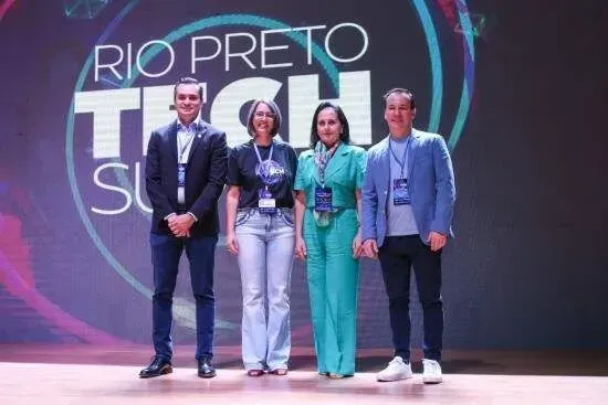 Um grupo de pessoas em pé em frente a uma placa que diz rio preto tech