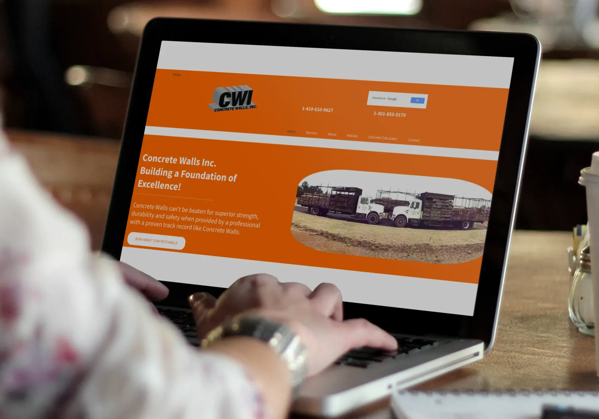 Person using a laptop showing an orange website with a truck image on screen