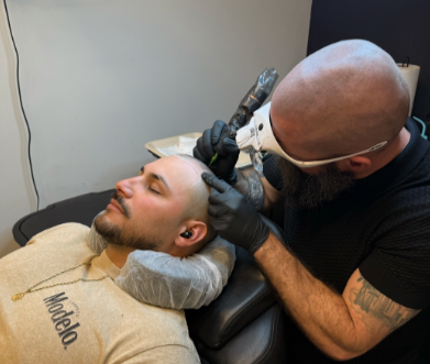 An SMP INK CDA Student Practitioner drawing the reference line on the scalp of an SMP client in a class setting.