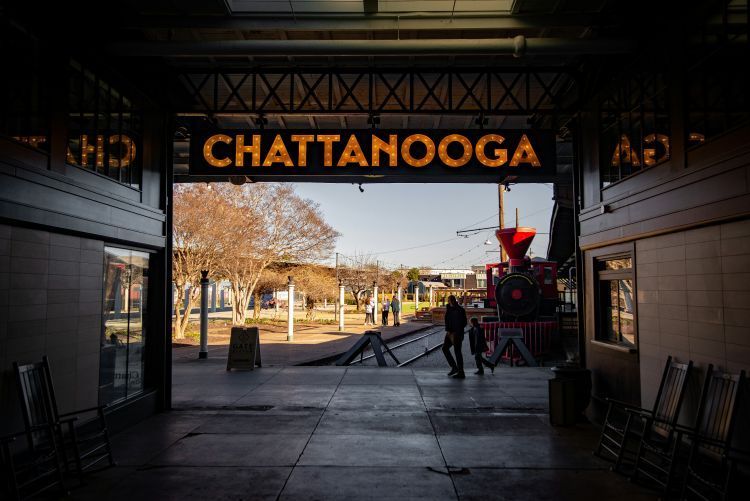 Chattanooga sign inside a tunnel, with a red train and people silhouetted in the opening beyond