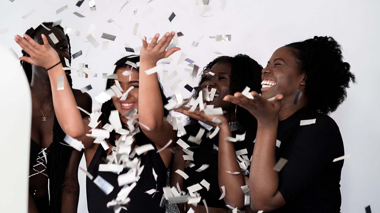 People celebrating as confetti falls, smiling and raising their hands