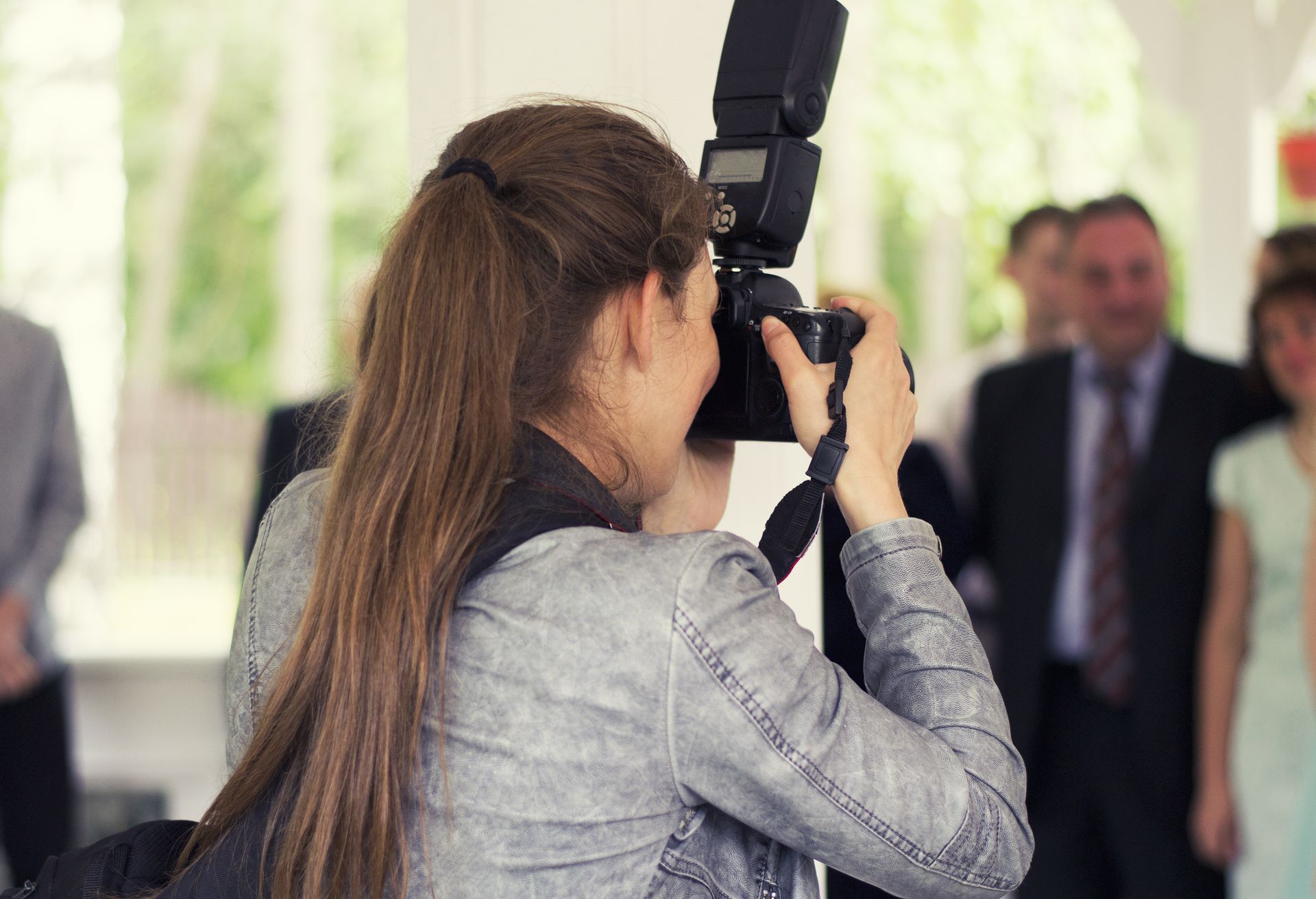 Photographer with flash taking a portrait at an indoor event, with blurred people in the background